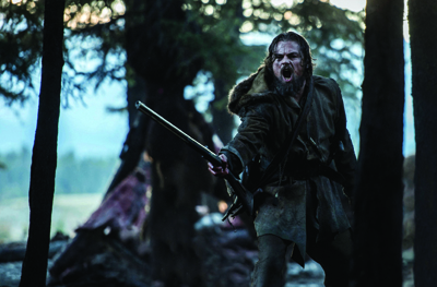 A man with a beard and fur-lined coat shouts while holding a rifle in a dark forest.