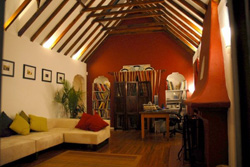 A living room with high vaulted ceilings, exposed wooden beams, a white sofa, and a red accent wall.