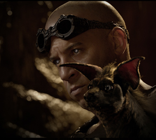 A bald man wearing dark goggles looks past a small, dark-furred animal with large ears.