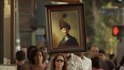 A framed classical portrait of a man in a hat held up amidst a crowd on a city street.