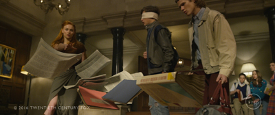 A woman catches flying papers in a large hall as two young men stand nearby.