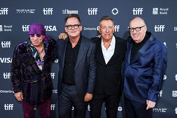 Four men in formal and semi-formal attire posing in front of a TIFF branded backdrop.