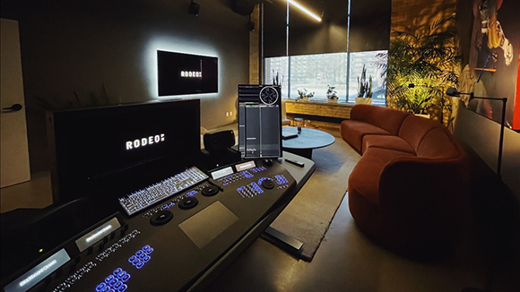 A dark editing studio featuring a large control console, monitors, and a red velvet sofa.