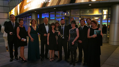 A group of people in formal wear posing for a photo in front of a building at night.