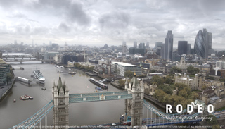 Aerial cityscape of London featuring the River Thames, Tower Bridge, and various skyscrapers under a cloudy sky.