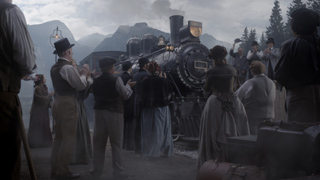 People in 19th-century attire stand near a large black steam locomotive on a cloudy day.