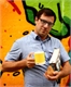 A man in a blue shirt holds a yellow mug and a book in front of colorful graffiti.