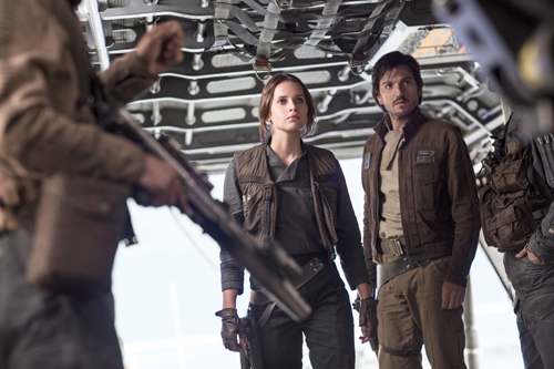 A woman and a man stand inside a metallic spacecraft bay surrounded by equipment.