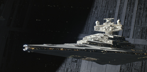 A large, wedge-shaped white starship with glowing lights floating in space near a massive structure.