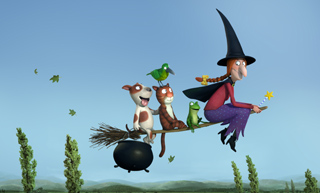 A witch in a tall hat flies on a broomstick with a dog, cat, parrot, and frog against a blue sky.