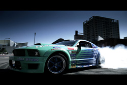 A light green sports car drifting with thick white smoke billowing from the rear tires.