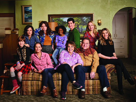 A group of twelve people of various ages posing together in a living room.