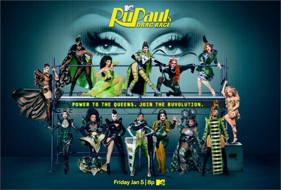 A group of drag queens in colorful, elaborate costumes posing in front of a large pair of eyes.