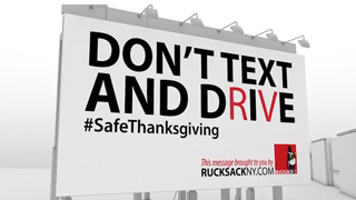 A white billboard reads 'DON'T TEXT AND DRIVE' in large black and red letters with #SafeThanksgiving below.