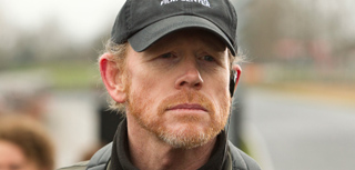 Close-up of a man with reddish hair and a beard wearing a black cap and a headset.