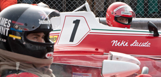 A driver in a black helmet in the foreground and a driver in a red helmet inside a red race car with the number 1.