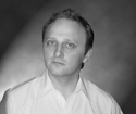Black and white portrait of a man in a light-colored collared shirt looking toward the camera.