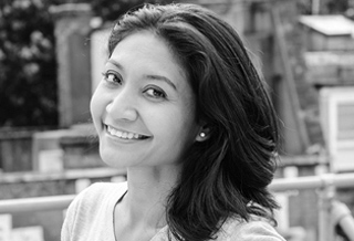 A smiling woman with dark hair looks toward the camera in a black and white portrait.