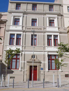 A multi-story beige building with red-framed windows and the text SAE INSTITUTE on the front.