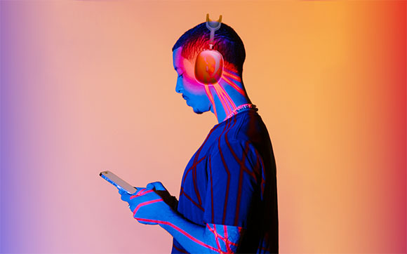 A person in profile with blue and red light patterns on their skin, holding a smartphone against a colorful background.