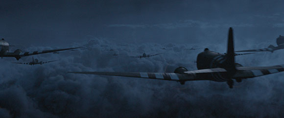 Multiple military aircraft flying in formation above a thick layer of dark clouds at night.