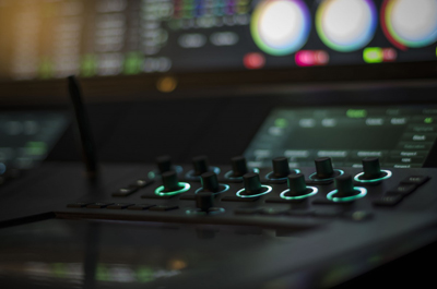 Close-up of a dark control panel with glowing green rings around several knobs and buttons.