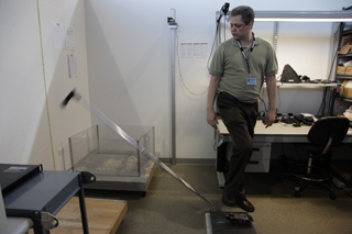 Man operating a device over a scale in a laboratory setting.