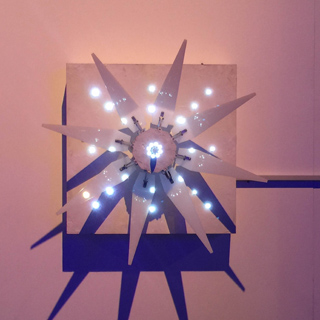 A starburst light fixture with multiple points and illuminated bulbs casts a shadow on a wall.