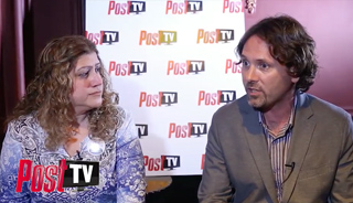 A woman with curly hair and a man in a blazer sit in front of a white Post TV logo backdrop.