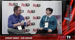 A man in a blue plaid shirt talks to a woman in a teal shirt during a Post TV interview.