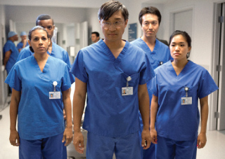 A group of diverse medical professionals in blue scrubs standing together in a hospital hallway.