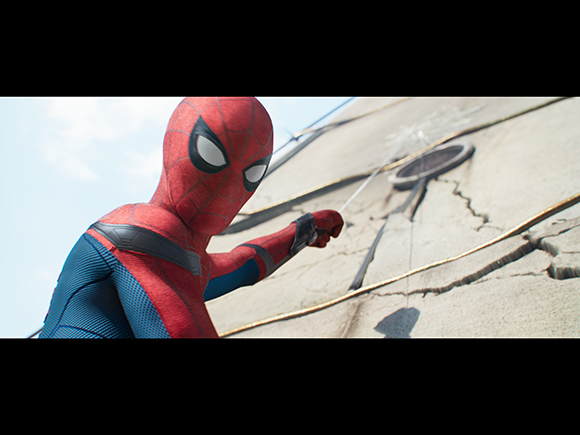 Spider-Man in a red and blue suit shooting a web toward a cracked stone wall.
