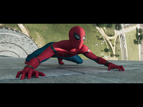 Spider-Man in a red and blue suit crouches on a high concrete ledge overlooking a park.