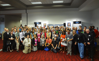 A large, diverse group of people standing together for a group photo in a large indoor conference room.
