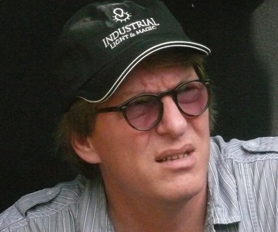 A man wearing a black Industrial Light & Magic cap and dark-tinted glasses looking upward.