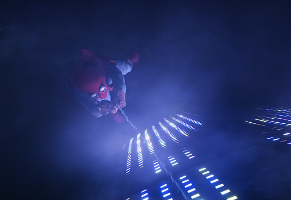 A person in a red and grey costume swings through dark blue smoke toward a grid of glowing blue lights.