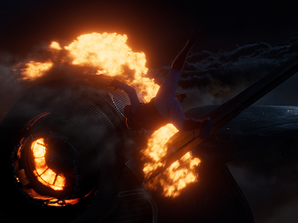 A person falls through bright orange flames near a large, dark jet engine in a dark sky.