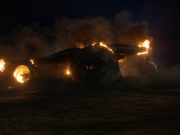 A large airplane on fire with thick smoke rising against a dark night sky.