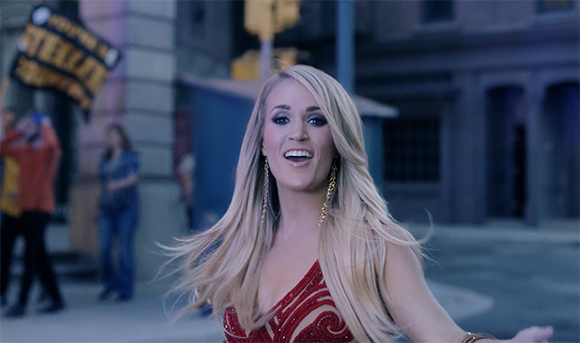 A blonde woman in a red sequined top smiles while standing on a city street.