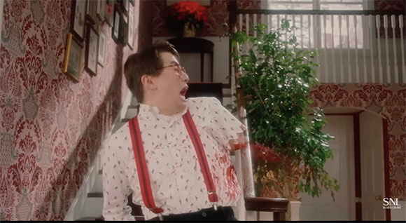 A man wearing glasses and red suspenders looks upward with a wide-mouthed expression of shock.