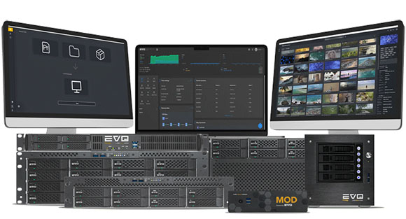 Three computer monitors displaying data and media above several black server rack units.