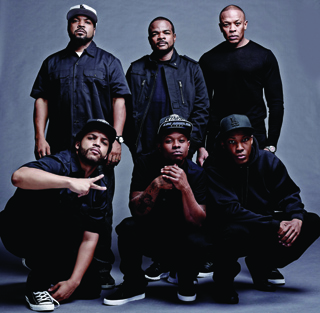 Six men wearing black clothing and baseball caps posing against a gray background.