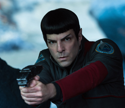 A man with dark hair and pointed ears aims a handheld device forward in a dark uniform.