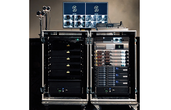 Two black equipment racks filled with servers and hardware, topped with monitors showing video footage.