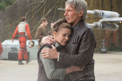 A man and woman in cinematic costume embrace closely in an outdoor setting with a starfighter in the background.