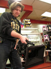 A man in a black sweatshirt uses a large professional video camera on a tripod in a store.