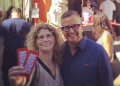 A smiling man with glasses and a woman with curly hair posing together outdoors.