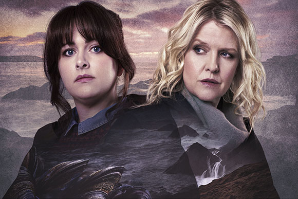 Two women with different hair colors looking ahead against a misty mountain landscape at sunset.