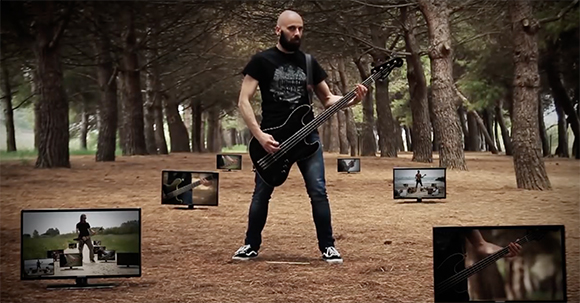 A man playing a black bass guitar in a forest, surrounded by several floating television screens.