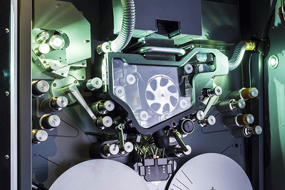Close-up of intricate industrial machinery featuring metallic rollers, gears, and silver components.